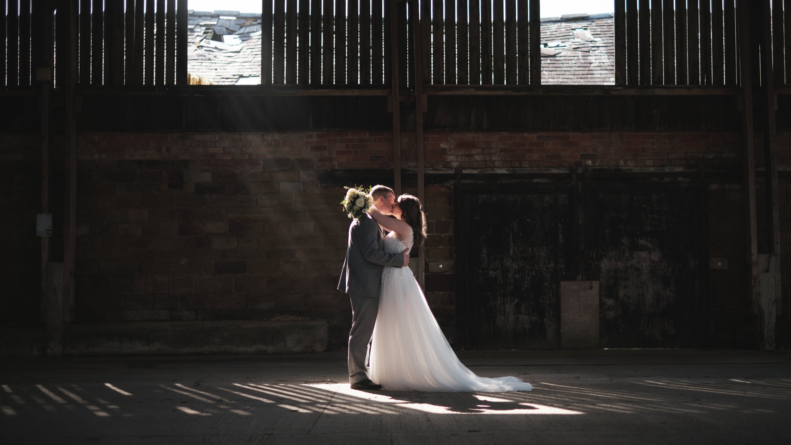 Couple kissing in a shaft of light inside an old barn