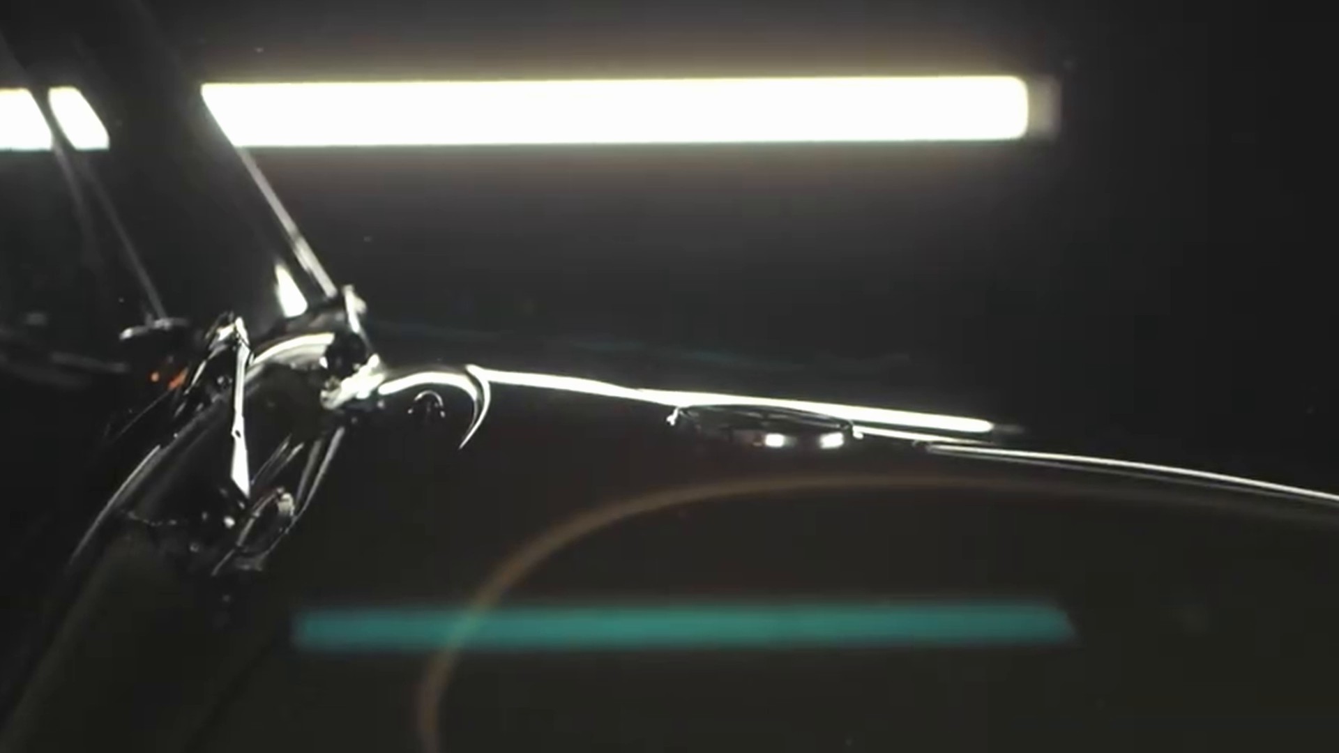Workshop light reflected along the curve of a classic car