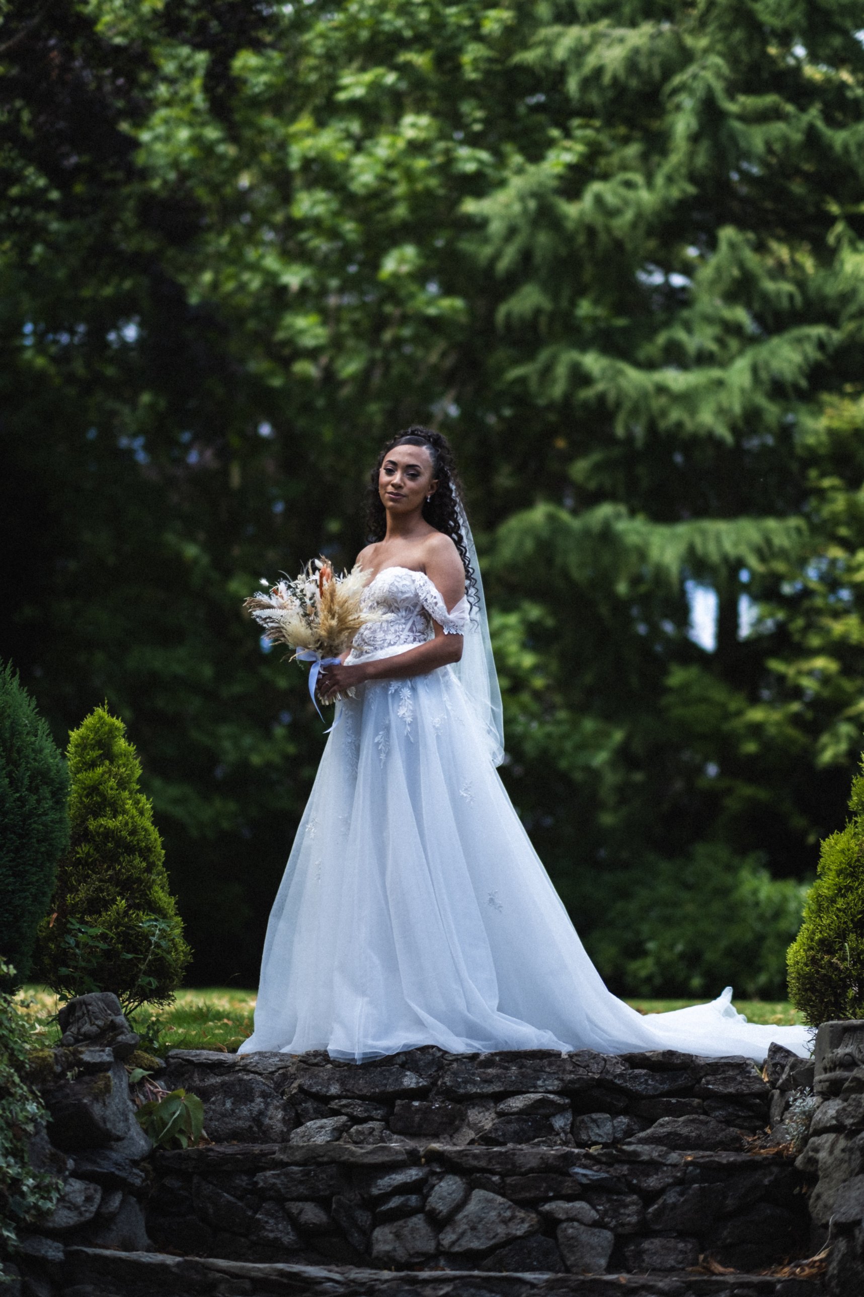 Bride standing on stone steps among trees