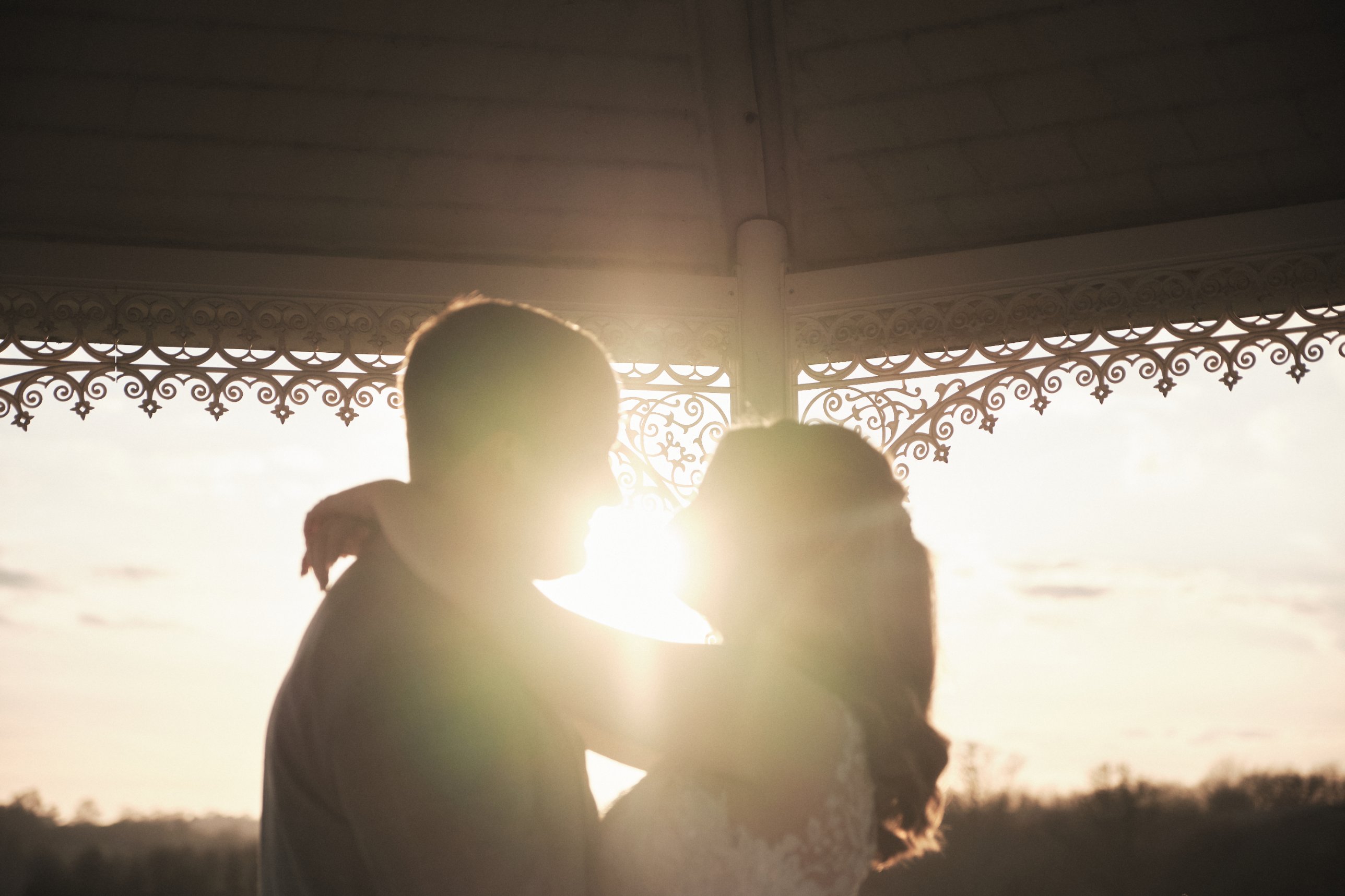 Close backlit embrace with sun flare under a gazebo